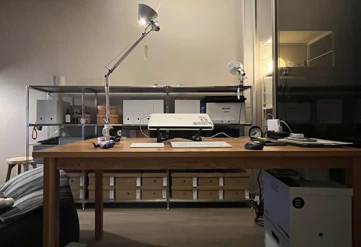A warm brown and neutral gray toned home office featuring a wooden desk, metal shelving, and tidy storage in a modern setting