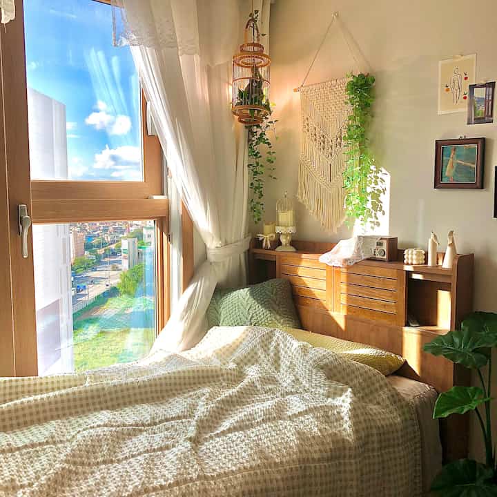 Bright sunlit bedroom with wood tones and white colors featuring a vintage-style bed and soft curtains, creating a cozy atmosphere