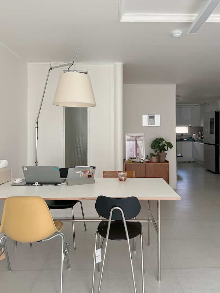 White and brown toned dining room featuring a modern dining table and multi-colored chairs arranged in a simple home office setup
