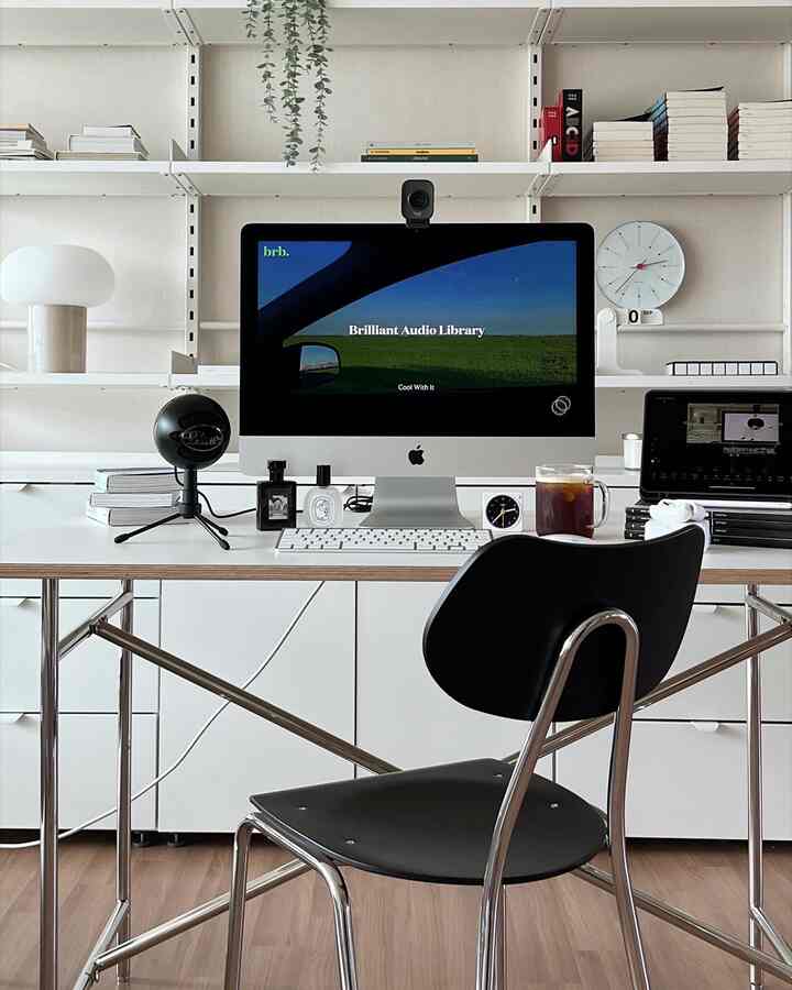 White and black toned home office featuring a computer and microphone in a simple modern workspace
