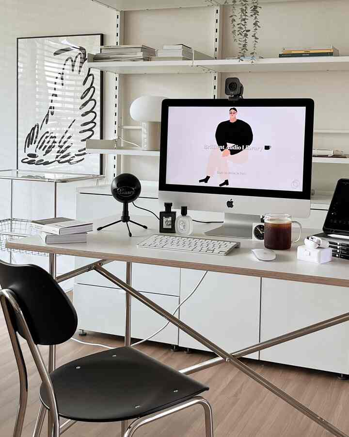 Modern white-toned home office featuring a white desk with black office chair, computer, and microphone arranged in a clean workspace