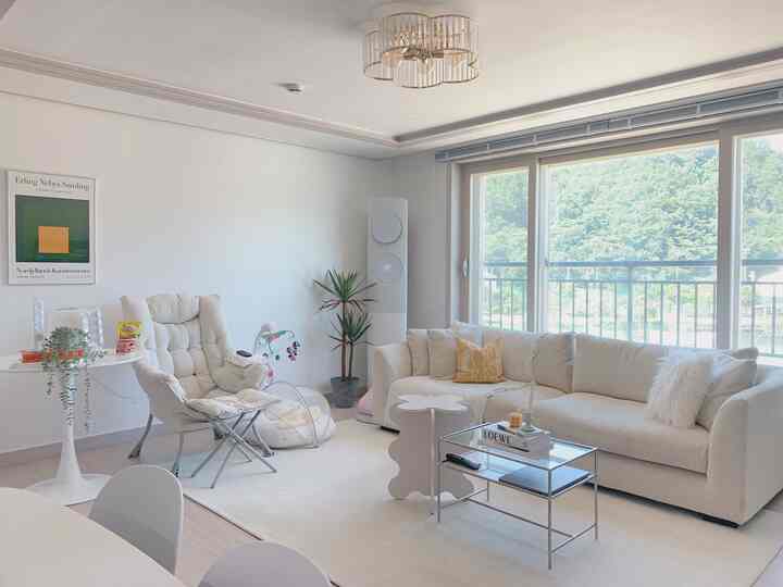 Bright and cozy living room in ivory and natural tones featuring cream sofa and baby items