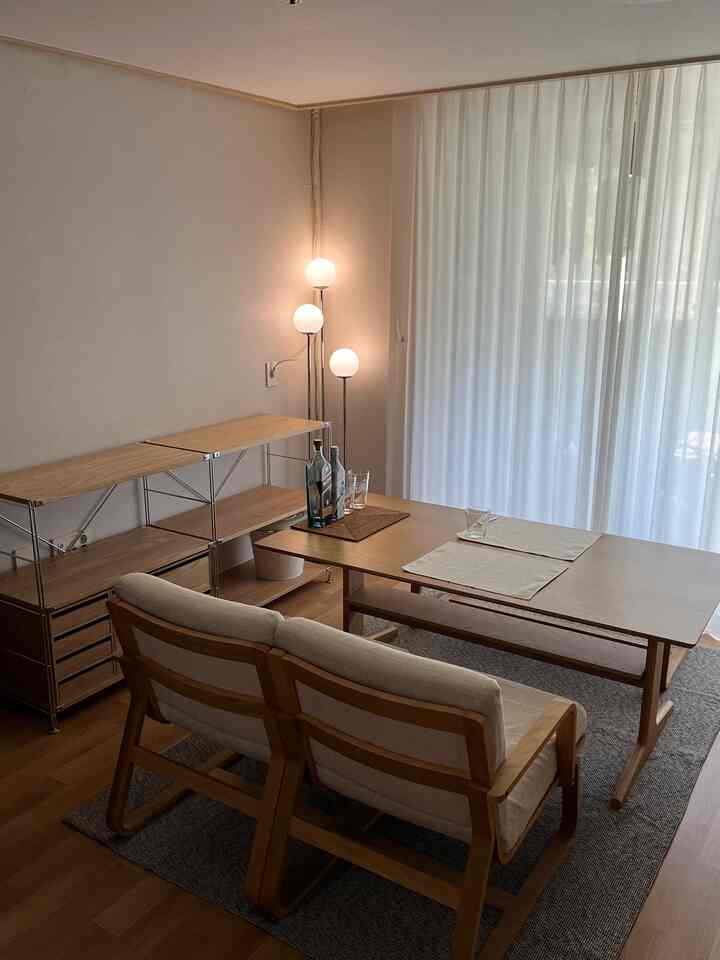 Natural tones featuring a living dining space with simple wooden furniture and sheer curtains letting soft light in