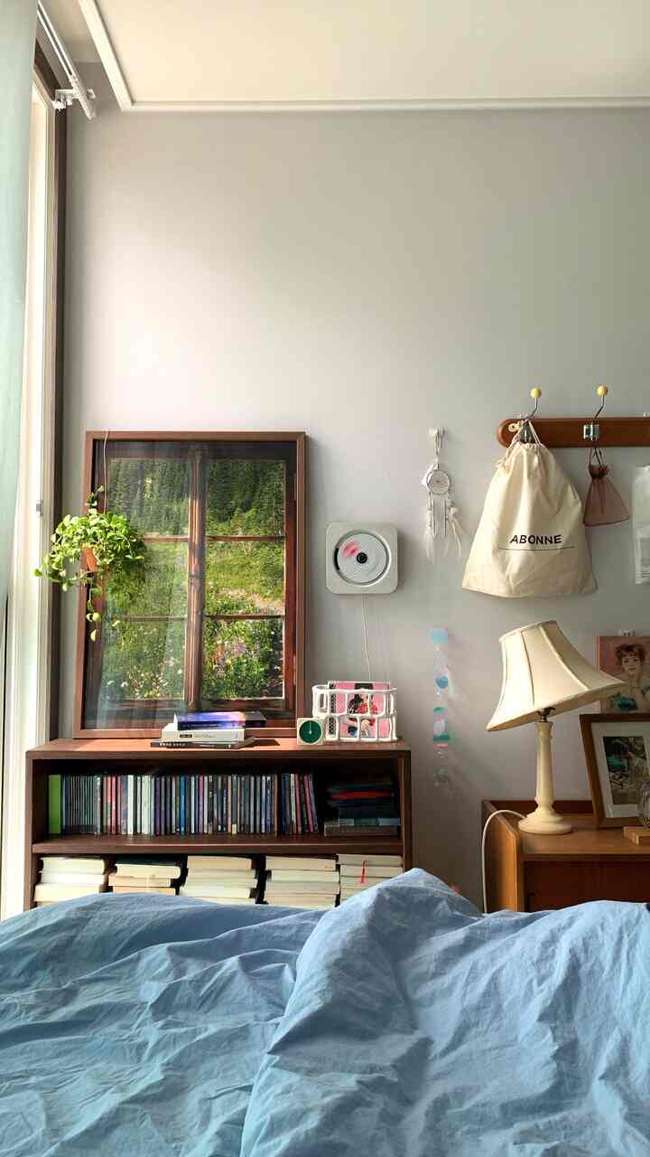 White walls and wood tone furniture in a bedroom featuring blue bedspread and framed artworks creating a cozy atmosphere