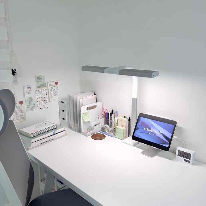 白を基調とした一人用の書斎スペース、デスクとLEDスタンド、整理された文房具が配置されたシンプルで清潔感のあるインテリア