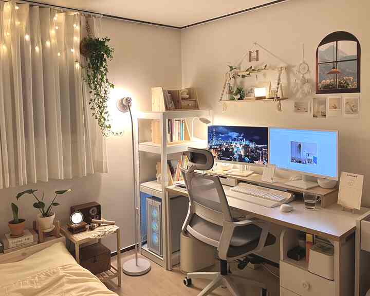 Natural-toned studio home office in white and beige featuring a desk with dual monitors, shelves, plants, and cozy lighting