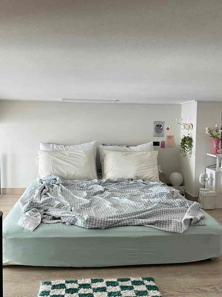 ミントとベージュの色調の寝室、シンプルでナチュラルなベッドと枕が配置された、落ち着いた清潔感のあるインテリア