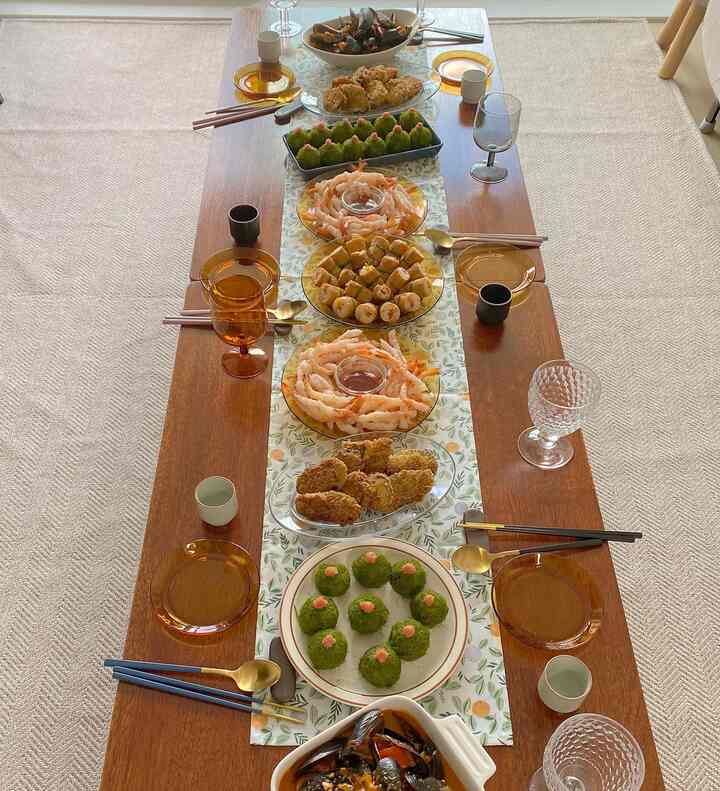 Warm orange-toned dining room featuring a long wooden table with assorted dishes and a table runner set for a home party