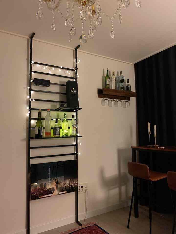 ブラウンのレザー椅子と黒いラダースタイルのホームバー、ストリングライトが配された雰囲気のあるダイニングルーム