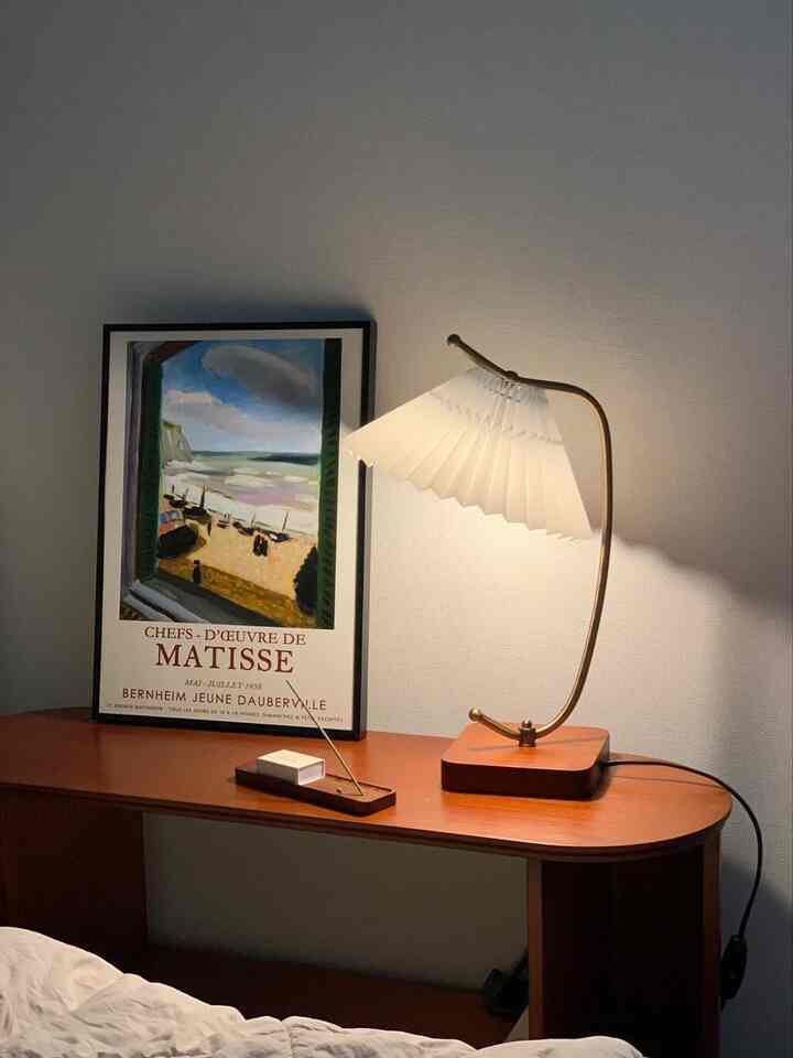 Natural brown cabinet and white lamp with framed poster, arranged in a simple cozy bedroom corner