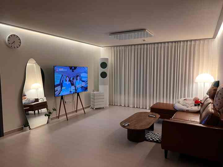 Modern living room in white and brown tones featuring sofa, coffee table, TV stand with a clean, cozy atmosphere