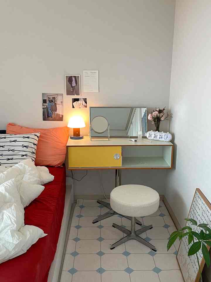 Modern compact bedroom vanity with a yellow door and red bedding creating a cozy atmosphere
