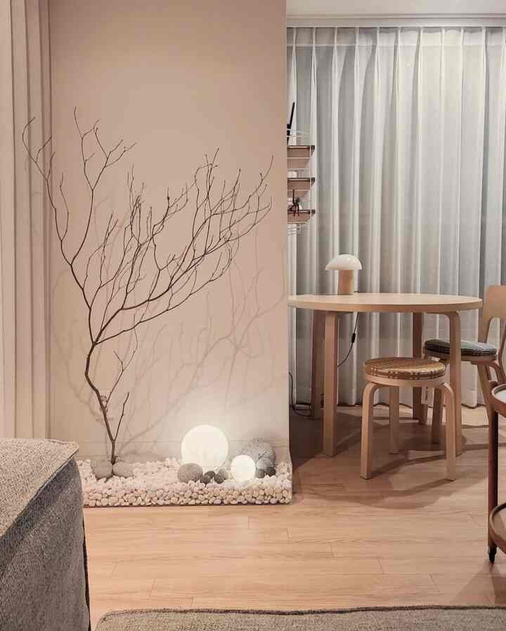 Natural beige-toned studio apartment dining space featuring wooden table, stools, and soft lighting in a cozy setting