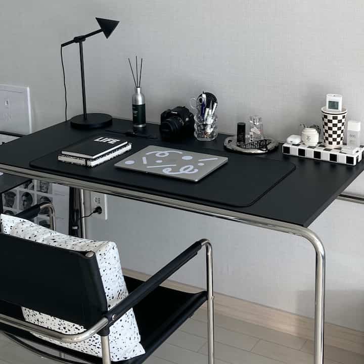 Modern home office study in black and white tones featuring a sleek desk and armchair with a clean setup