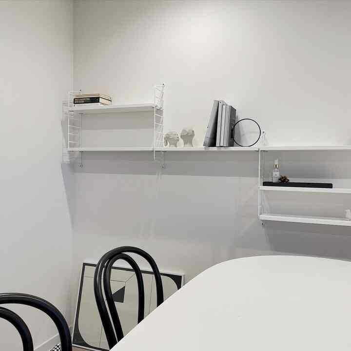 White-toned dining room featuring a white dining table and black chairs in a minimal setting