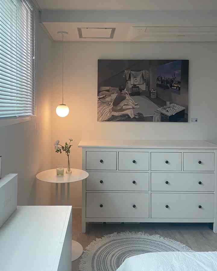 White and wood tone bedroom featuring a large dresser and modern framed art, creating a clean natural modern atmosphere