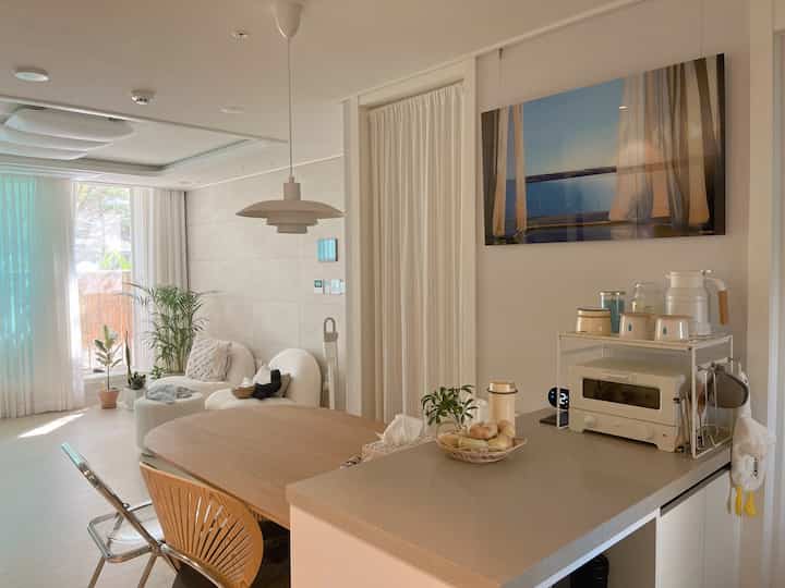 ナチュラルでホワイトとベージュの色調のキッチンとリビングが調和した雰囲気のあるインテリア