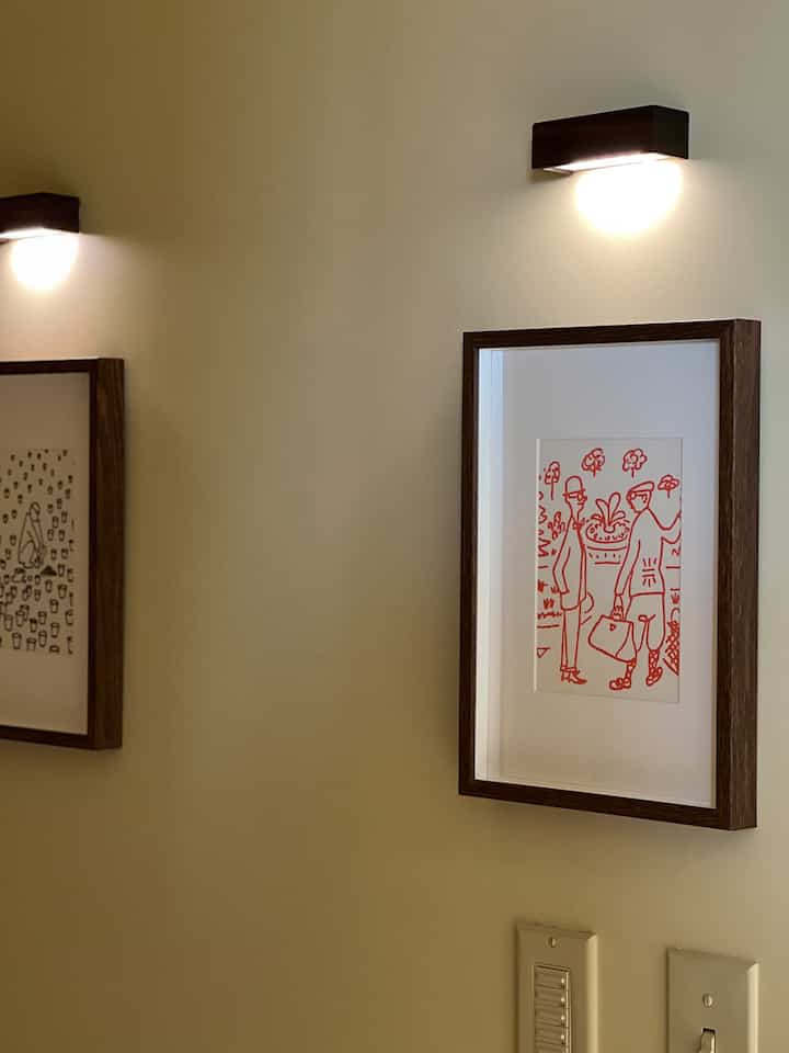 Warm beige-walled entrance featuring wood-tone picture frames and wall sconces creating a cozy, elegant atmosphere