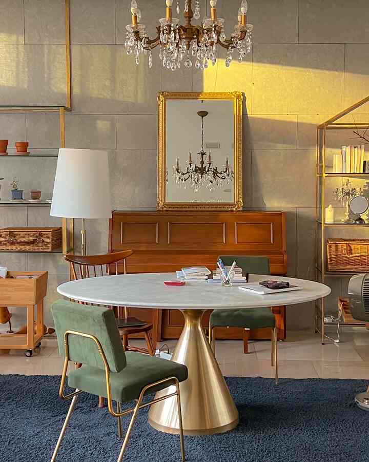 ゴールドとナチュラルな色調のリビング・ダイニング空間、大理石のテーブルとピアノ、クラシックなシャンデリアが配置された雰囲気のあるインテリア