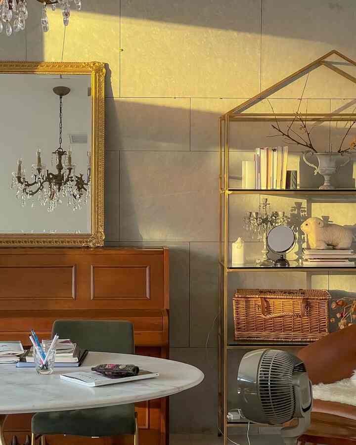 Brown and gold toned living room featuring antique gold wall mirror and gold-framed bookshelf with vintage atmosphere