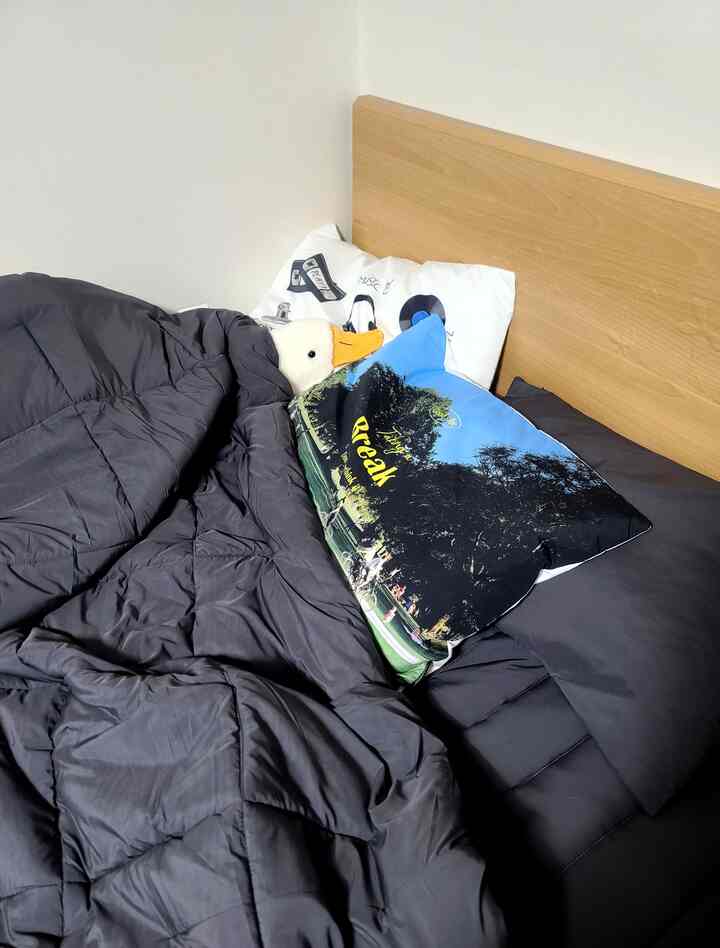 Dark gray bedding in a bedroom featuring a wood tone bed headboard and retro style pillows creating a cozy atmosphere