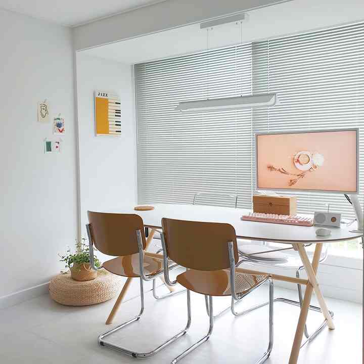 White and brown toned dining room combined with home office, featuring simple modern furniture and aluminum blinds