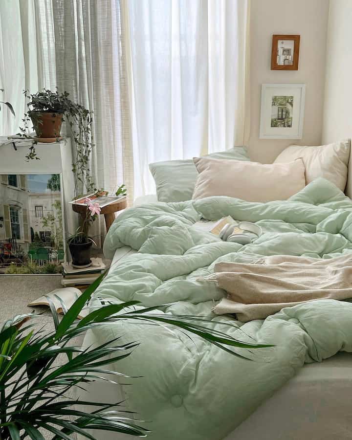 Soft and natural bedroom featuring fresh mint-colored bedding and arranged plants