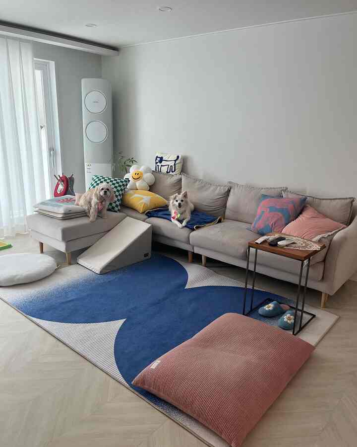 A bright beige sofa and blue carpet in the living room featuring two dogs and various cushions, creating a cozy natural modern interior