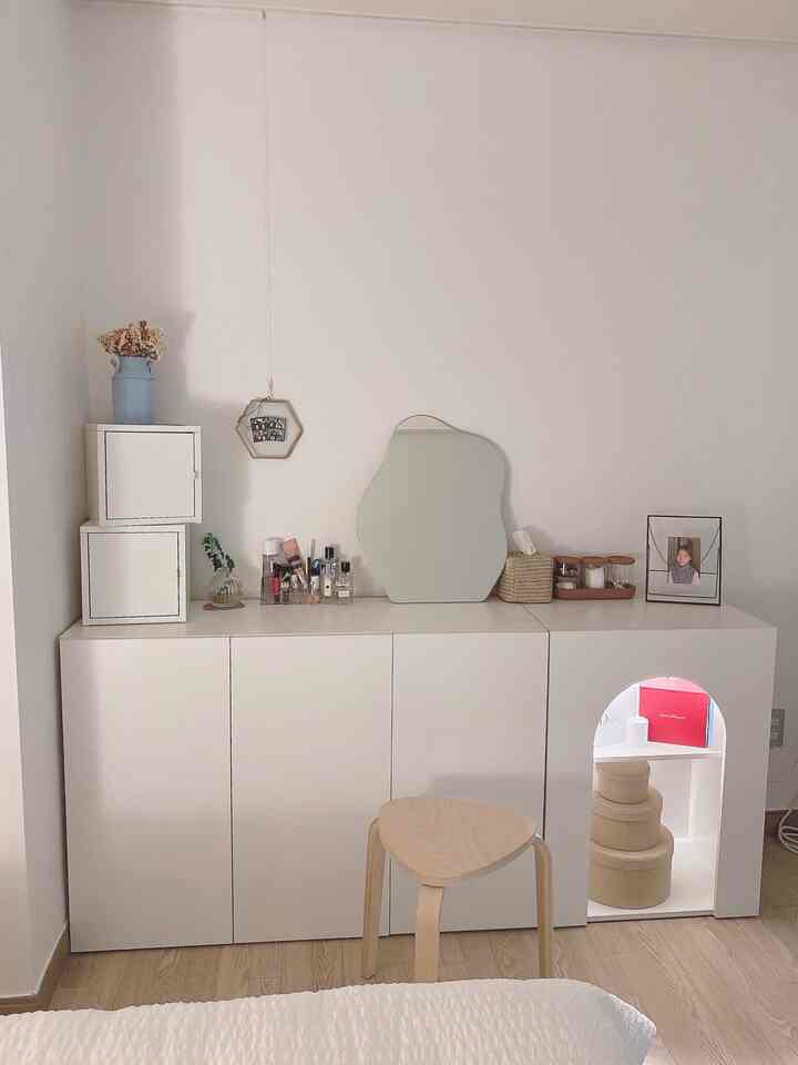 White-toned bedroom space featuring a vanity and fireplace storage cabinet with a clean, simple modern interior
