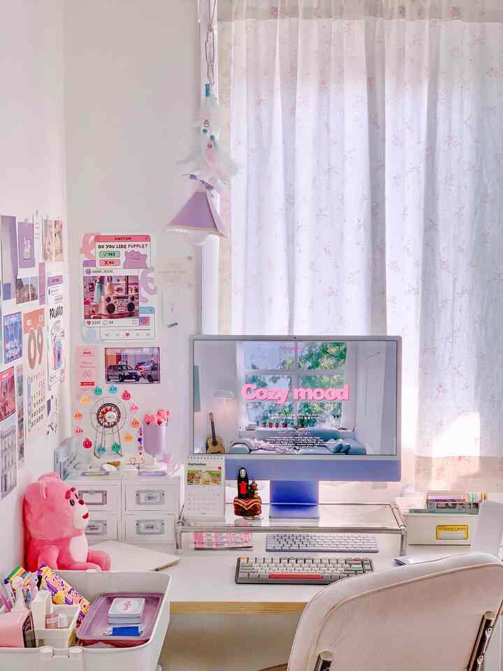 白とピンクのトーンのホームオフィス、コンピューターと整理されたデスク周りの小物が配置された雰囲気のある空間