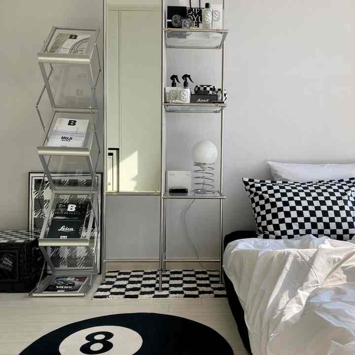 White and black bedroom space featuring checkered pillows and an 8-ball rug with a modern, clean hotel-like interior