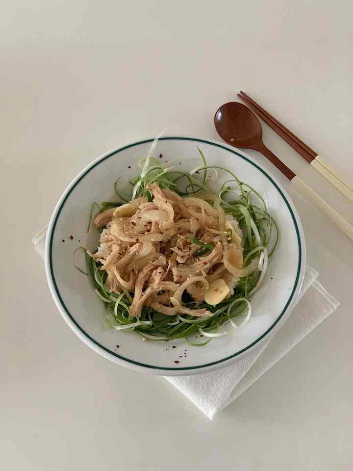 Natural toned kitchen setting featuring a plate of chicken breast dish with wooden cutlery on a clean table surface