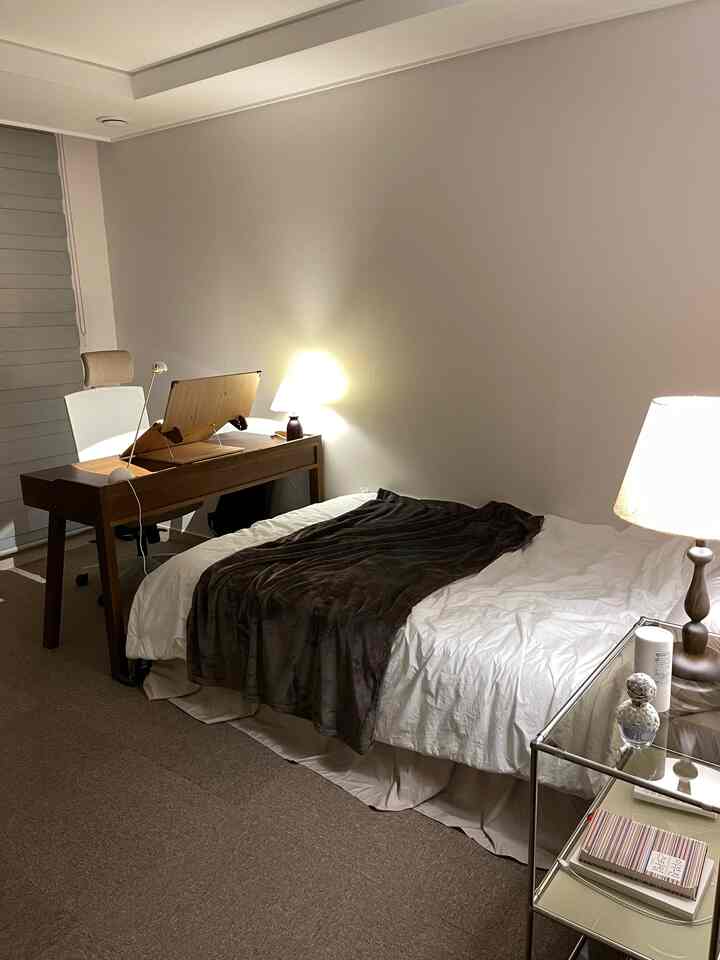Natural tone bedroom with dominant brown hues, featuring a desk and nightstand in a cozy setup