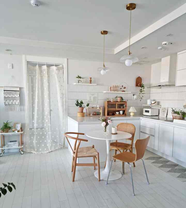 明るい白と温かみのある木目調のキッチン、丸テーブルとダイニングチェアが配置された雰囲気のあるインテリア