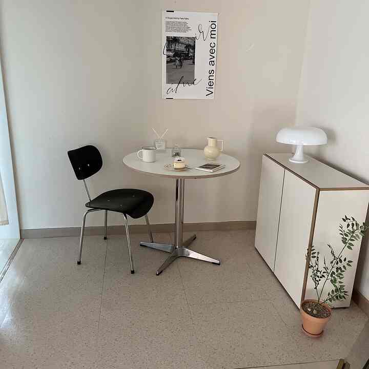 白い壁と丸テーブル、黒い椅子が配置された居心地の良いカフェ風ナチュラルな空間