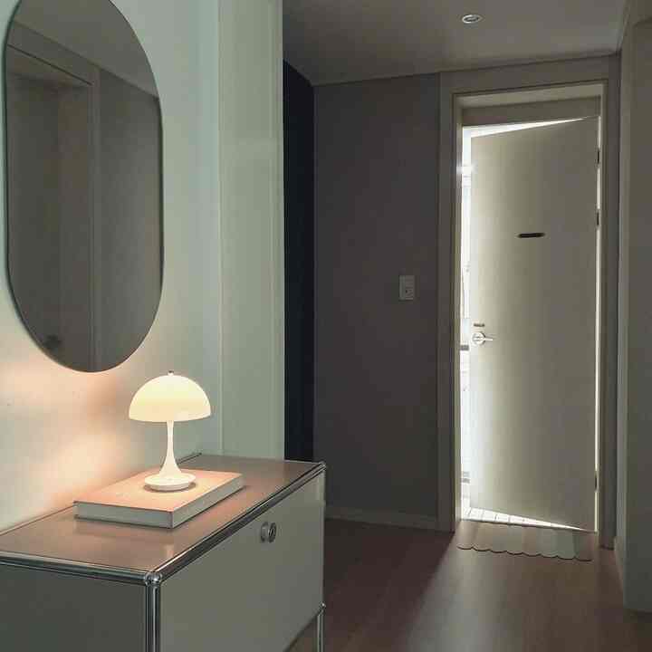 White and wood tone restroom featuring an oval mirror and table lamp on a clean vanity