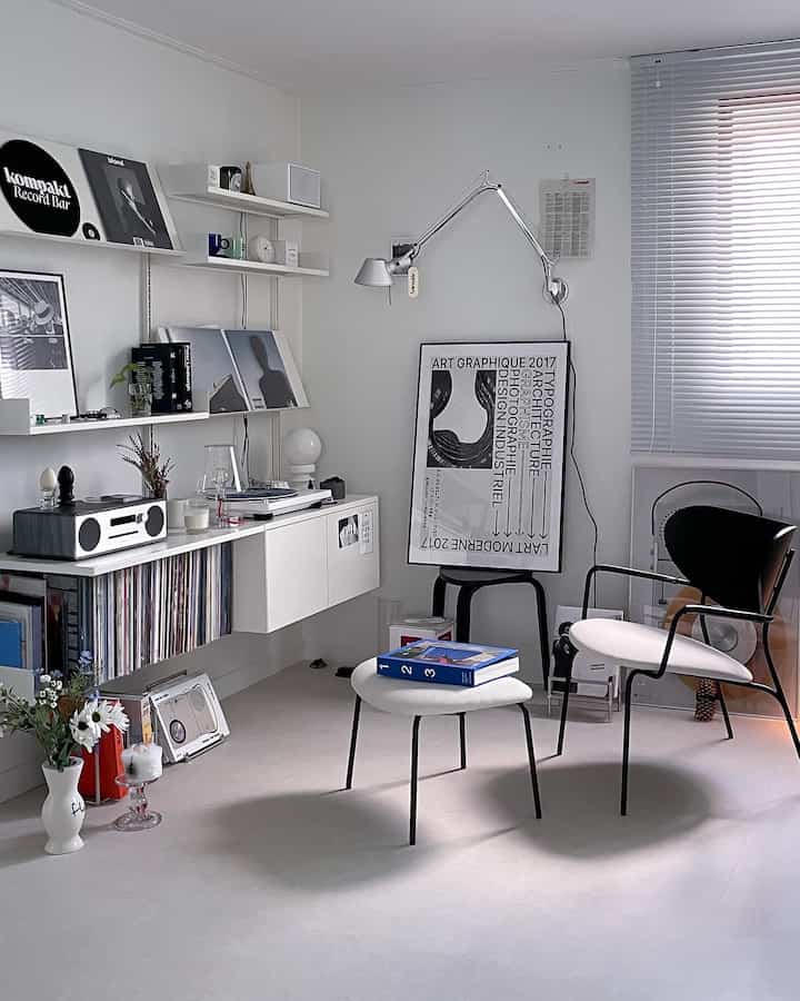 Modern living room in white and black tones featuring wall shelves and a record player, creating a clean and stylish atmosphere