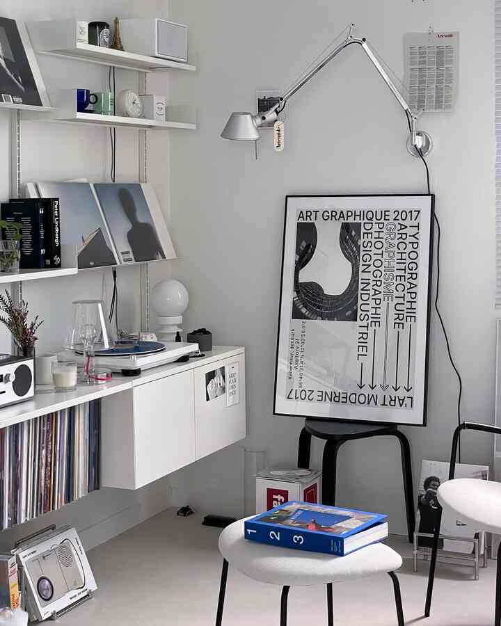 モダンなホワイトトーンのリビング、ターンテーブルとブラケットライトが配置され、清潔感のある音楽空間のインテリア