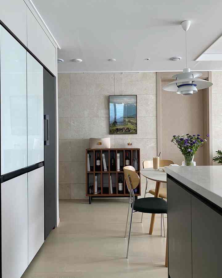 Natural and white toned dining room and kitchen space featuring dining table, chairs, and pendant light in a modern setting