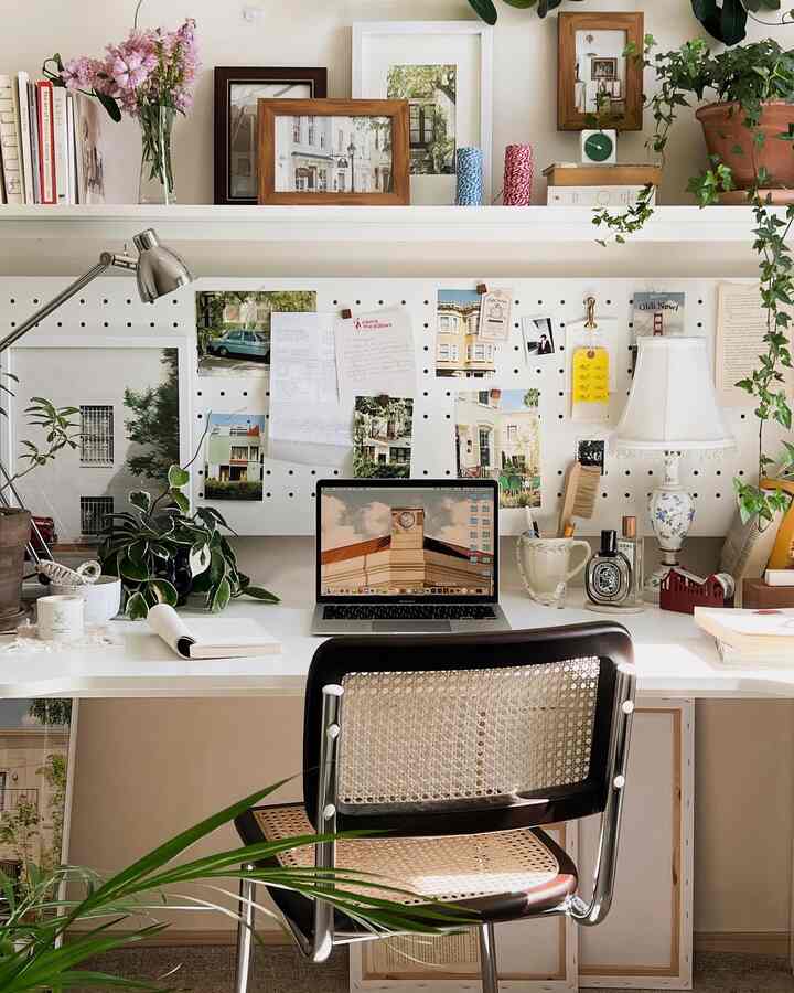 White and wood-tone home office featuring plants and picture frames, creating a cozy and neat workspace