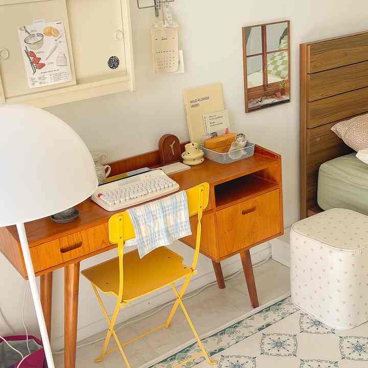 Natural-toned home office space featuring a yellow chair and wooden desk with cozy accents.