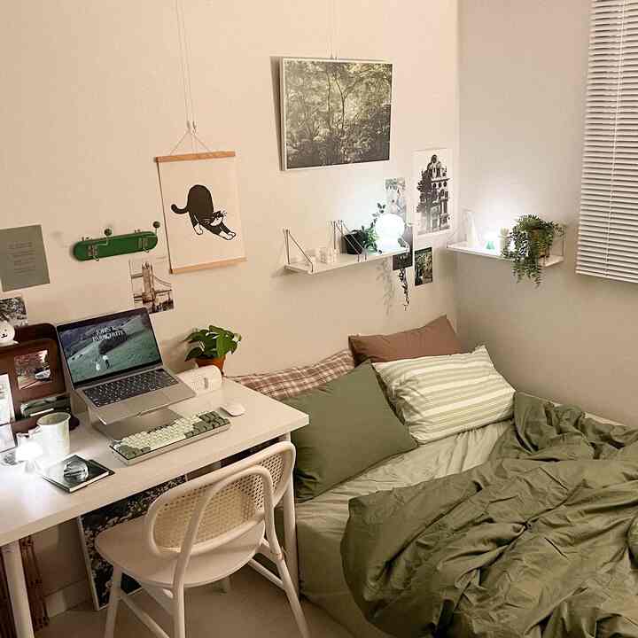 A cozy autumn interior bedroom in deep green and white tones, featuring a single bed, desk, shelves, plants, and mood lighting