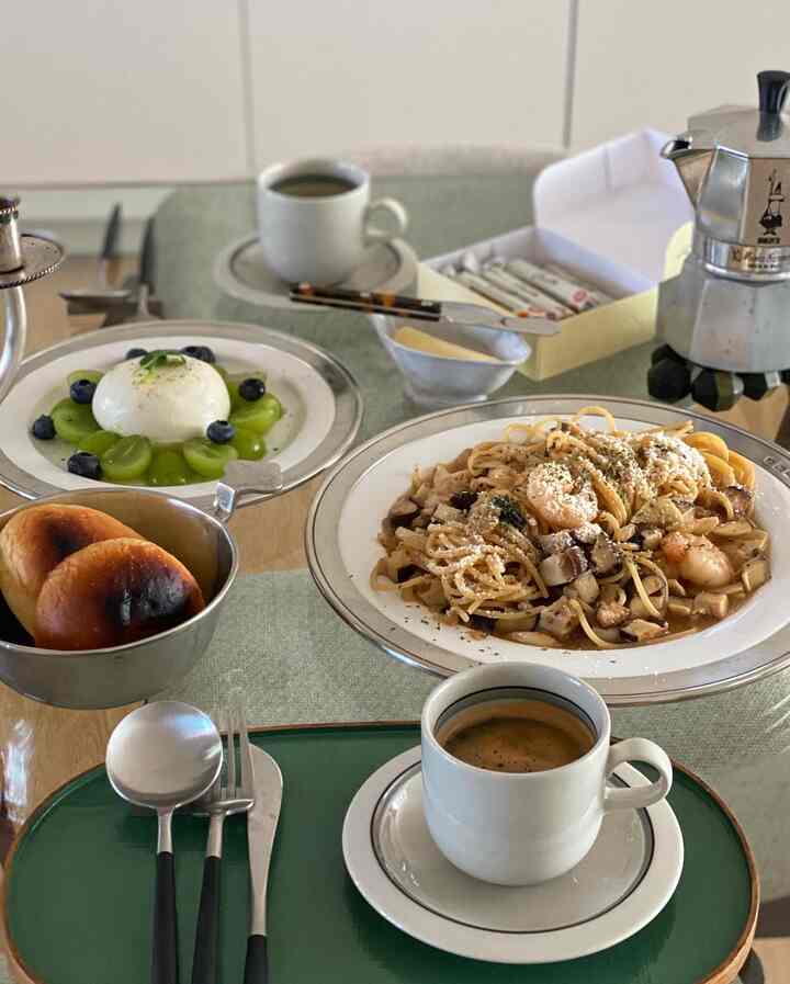 ナチュラルカラーとホワイトトーンのキッチンのダイニングテーブルにホームブランチが並ぶ、落ち着いた雰囲気のインテリア