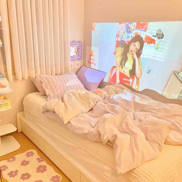 温かみのあるナチュラルトーンの寝室、快適なベッドとパステルピンクの寝具、壁にプロジェクター映像が映し出された空間