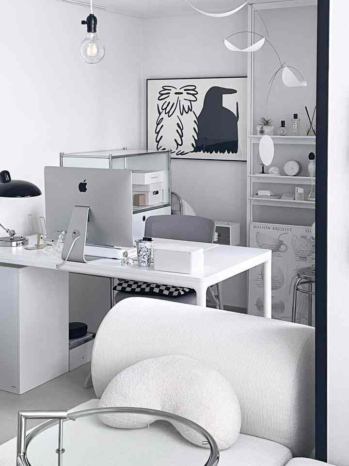 Modern home office space in white and gray tones featuring a white desk and sofa with a clean, minimal atmosphere