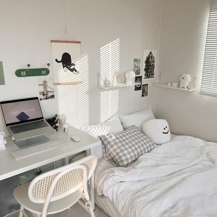 White-toned bedroom featuring a desk and pillows in a cozy, clean atmosphere