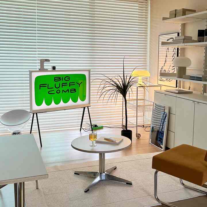 White-toned living room featuring a round side table and blinds with modern furniture in a clean setting