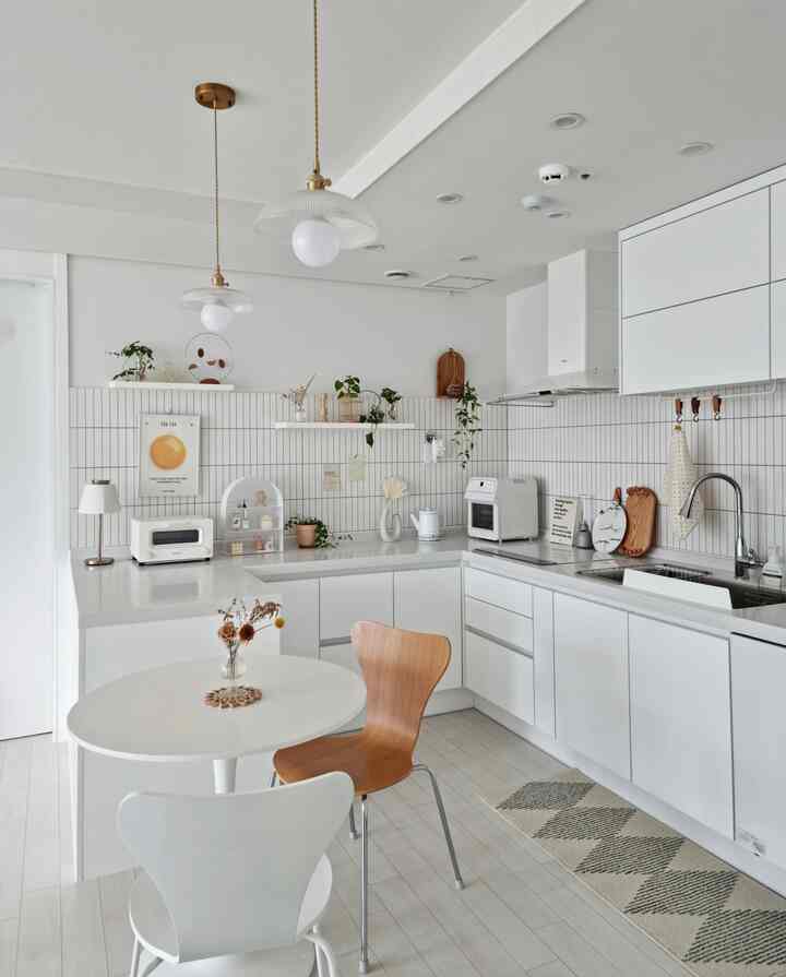 明るい白色のキッチンスペース、丸テーブルと木目調のチェアが配置された清潔感とナチュラルな雰囲気のインテリア