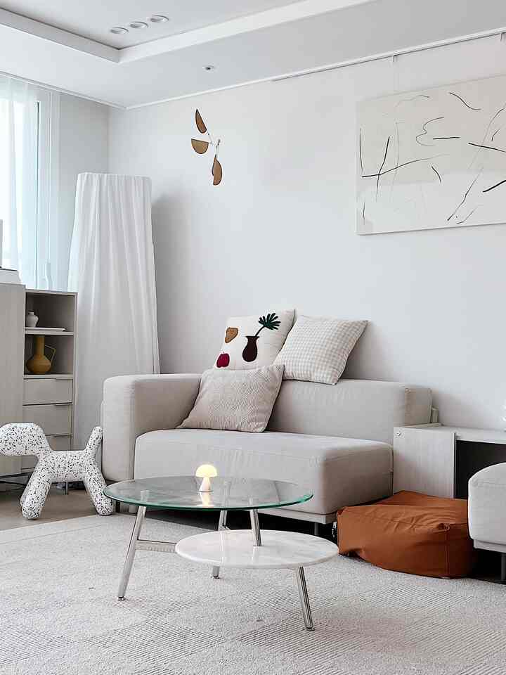 ホワイトトーンのリビング、モダンなソファとコーヒーテーブル、自然素材の装飾が配置された落ち着いた印象的なインテリア