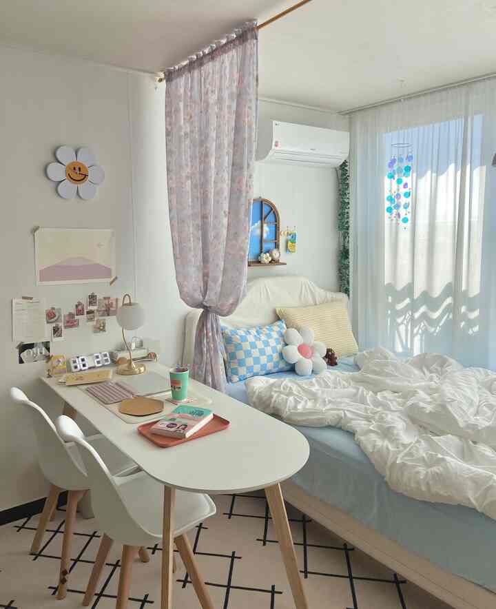 A cozy single household bedroom with white and pastel tones featuring a desk and bed forming a comfortable home office space